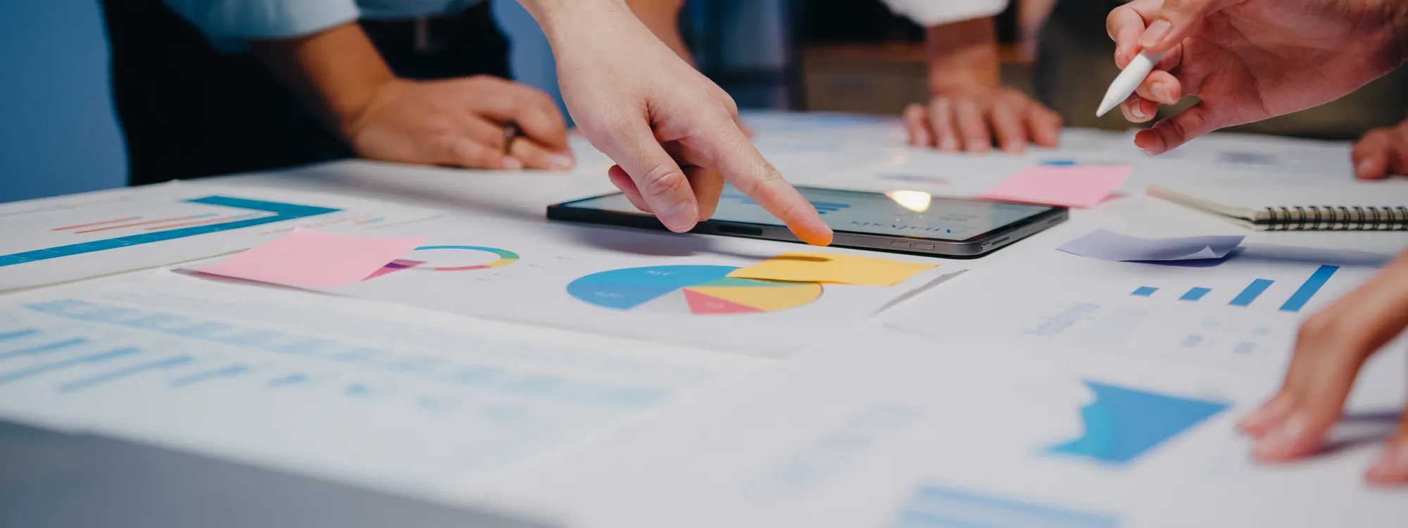 Equipe analisando gráficos e anotações sobre uma mesa de trabalho